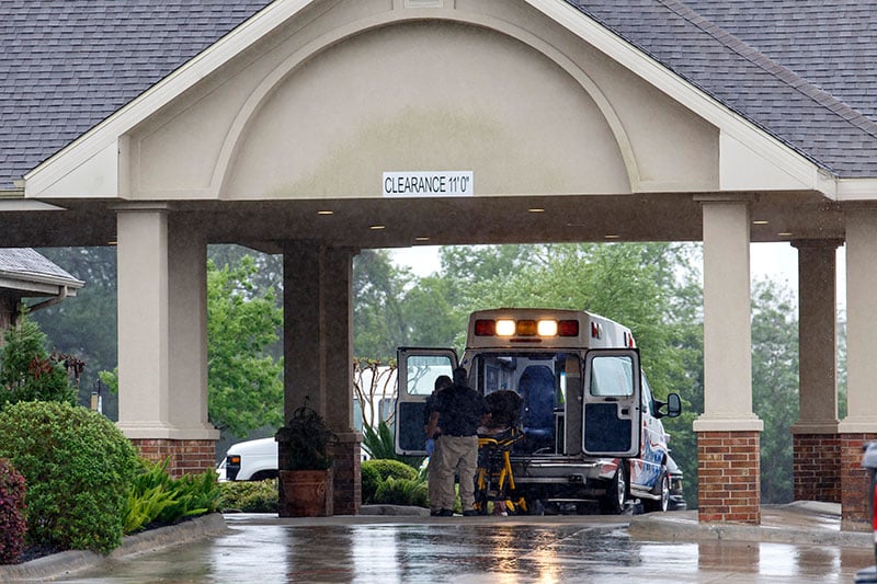 Paramedics disinfect a gurney in their ambulance before leaving a 131-bed nursing home in Tomball.