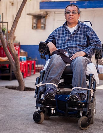Santiago Arias in his wheelchair in front of his home in Mexico City. Photo by Justin Dehn.